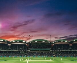 people watching game of cricket during sunset