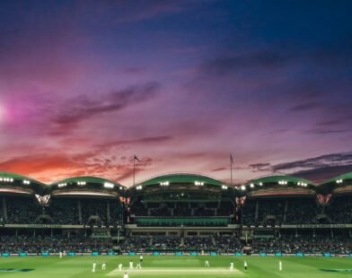 people watching game of cricket during sunset